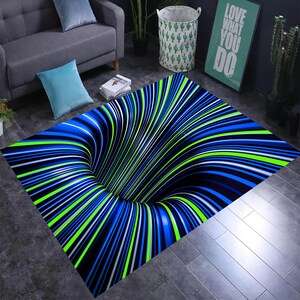 Peut inclure: Un tapis rectangulaire avec un motif d'illusion d'optique en 3D. Le tapis présente un centre noir qui semble être un trou, entouré de lignes courbes bleues, vertes et blanches. Le tapis est posé sur un sol gris.