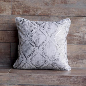 May include: A decorative throw pillow with a silver and white geometric pattern. The pillow has a subtle distressed look and is perfect for adding a touch of elegance to any room.