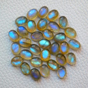 May include: A collection of oval-shaped labradorite gemstones with iridescent blue and gold hues.