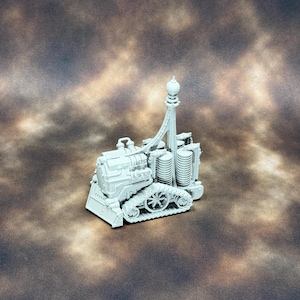 May include: A light grey miniature vehicle model featuring a tracked base, a front-mounted plough, and a tall central mast topped with a spherical finial. The structure includes cylindrical components and mechanical detailing on the main body.