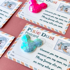 May include: Several "Pixie Dust" postcards with a Mickey Mouse theme. Each postcard features a sequined Mickey Mouse head in either pink or blue-green. The postcards have a vintage design with text and a stamp illustration.