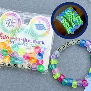 May include: A glow-in-the-dark bracelet kit with colorful beads and the word "MAGIC" spelled out on a bracelet. The kit includes a variety of translucent beads in shades of pink, green, blue, and orange. The packaging says "Have fun and keep shining!"