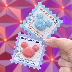 May include: Two decorative postage stamps with a light blue and pink Mickey Mouse design. The stamps read "MAGICAL MAIL" and "13¢". The stamps have a light blue border and the text "From one dreamer to another, keep shining".