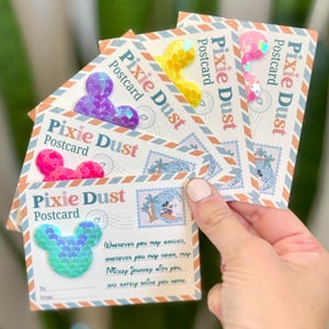 May include: A stack of "Pixie Dust" postcards with Mickey Mouse-shaped embellishments in various colors. Each postcard features a vintage stamp design with Mickey Mouse surfing. The text "Wherever you map wander, wherever you map roam, map Mickey journey with you, and safely bring you home."