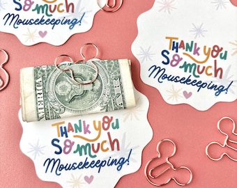 May include: White scalloped cards with the text Thank you so much Mousekeeping! in colorful letters, accompanied by rose gold metal paper clips shaped like mouse heads. One card holds a rolled-up one-dollar bill secured by a mouse-shaped clip.
