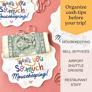 May include: White scalloped cards with the colorful text Thank you so much Mousekeeping! and small star and heart icons. A rose gold metal paperclip shaped like a mouse head holds a rolled US dollar bill. Additional clips are scattered nearby.