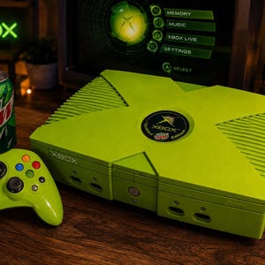 May include: A lime green Xbox console and matching controller, featuring a Mountain Dew Limited Edition circular logo on the top. The console has a large X-shaped design, front-facing controller ports, and the word Xbox printed on the front panel.