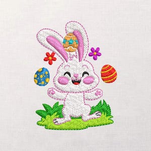 Puede incluir: Un diseño bordado de un conejito de Pascua blanco sonriente con orejas y mejillas rosas, rodeado de coloridos huevos de Pascua y flores. El conejito está de pie sobre un trozo de hierba verde, creando una imagen alegre y festiva.
