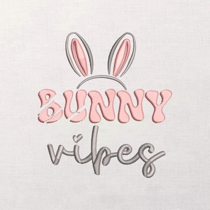May include: An embroidered design featuring bunny ears above the words "BUNNY vibes" in pink and gray thread. The design includes a small heart and is set against a white fabric background.