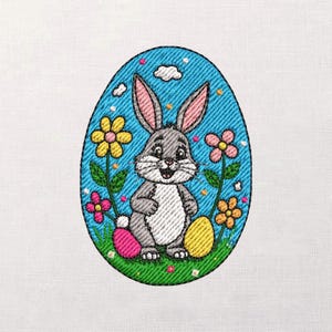 May include: Embroidered Easter egg design featuring a gray bunny with pink-lined ears, surrounded by colorful flowers and Easter eggs. The bunny is smiling, set against a blue background with white clouds. The design is on a white fabric.