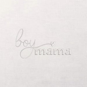 May include: White fabric with the embroidered words "boy mama" in a delicate, cursive font. The word "boy" is in a flowing script, connected by a line to the word "mama", which is in a block letter style. A small heart is above the "a" in "mama".
