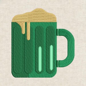 May include: A green beer mug with a handle, filled with golden foam that is overflowing. The mug has vertical lines and a light green accent. The design is embroidered on a beige fabric.