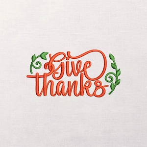 May include: An embroidered design on a white background features the words "Give thanks" in orange script. Green leafy accents frame the text, creating a festive and decorative appearance. The design is suitable for fall and Thanksgiving.