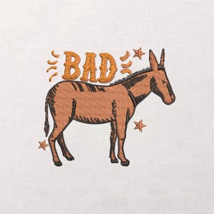 May include: Embroidered design featuring a brown donkey with the word "BAD" in orange above it, along with star accents. The donkey is depicted in a side profile, with detailed stitching on a white background.