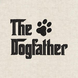 Puede incluir: Diseño bordado sobre tela beige claro. El texto "The Dogfather" está escrito en negrita y en negro, con una huella de pata que reemplaza la "O" en "Dog". El diseño es para amantes de los perros.