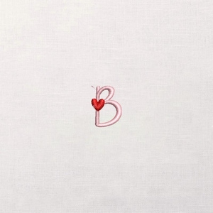 Peut inclure: Une lettre "B" rose brodée avec un cœur rouge. La lettre est cousue dans un style délicat et cursif, et le cœur est positionné à gauche de la lettre. Le fond est un tissu blanc uni.