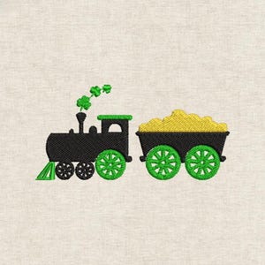 May include: Embroidered design of a black train with green wheels and accents, pulling a cart filled with yellow treasure. Green shamrocks form the smoke from the train's smokestack. The design is on a light beige fabric.