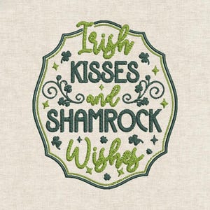 Könnte beinhalten: Gesticktes Design mit den Worten "Irish Kisses and Shamrock Wishes" in Grün und Dunkelgrün. Der Text befindet sich in einem dekorativen, geschwungenen Rahmen mit Kleeblättern und Sternen. Der Hintergrund ist ein hellbeiger Stoff.