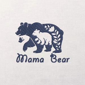 May include: Embroidered design featuring a dark blue Mama Bear with a white cub, a butterfly, and floral accents. The words "Mama Bear" are written in a cursive font below the bears. The design is on a white fabric.