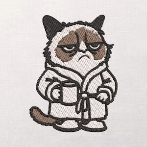 Op de afbeelding: Geborduurde patch met een chagrijnige kat in een badjas, die een mok vasthoudt. De kat heeft een bruin en wit gezicht met een chagrijnige uitdrukking. De witte badjas heeft zwarte randen en de mok is wit.