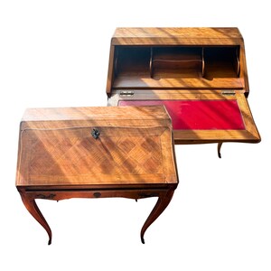 Peut inclure: Deux secrétaires en bois avec une finition brun clair. Un bureau est fermé, montrant un placage à motif losange et une serrure en métal. L'autre bureau est ouvert, révélant une surface d'écriture en cuir rouge, des compartiments et des pieds galbés.