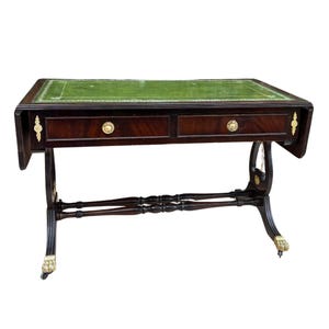 May include: A mahogany writing desk with a green leather top. The desk has two drawers with brass knobs and decorative brass accents. The legs are curved and feature brass claw feet. A classic piece of furniture.