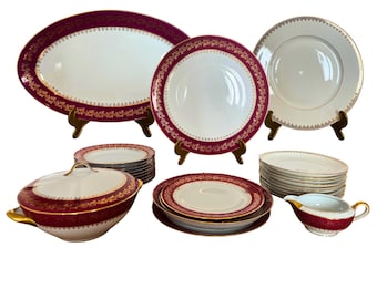 Vajilla de porcelana de Limoges, 26 piezas para 9 personas, friso rojo rubí y ribete dorado, circa mediados del siglo XX.
