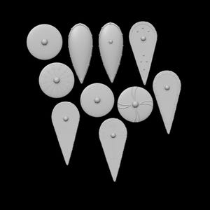 May include: A selection of ten light grey shields in different shapes and sizes, set against a black backdrop. The shields include round, teardrop, and pointed designs, some with decorative features such as rivets or embossed patterns. All shields share the same colour.