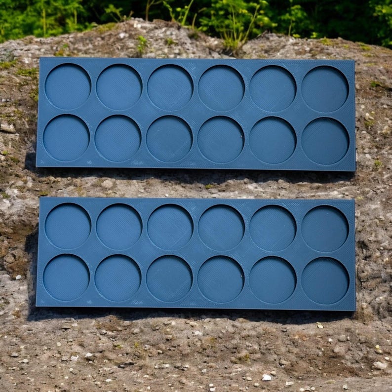 May include: Two blue plastic trays with 12 circular depressions each. The trays are designed to hold small round objects, such as paint pots or other craft supplies.