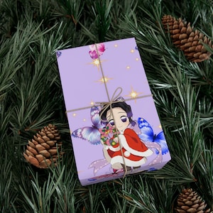 Può includere: Una confezione regalo avvolta con uno sfondo viola, con un personaggio anime e farfalle. La scatola è legata con spago e posta su uno sfondo di aghi di pino e pigne.