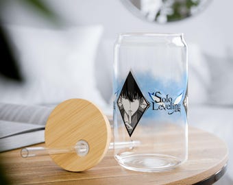 Op de afbeelding: Een doorzichtige, blikvormige tumbler met een bamboe deksel en rietje. De tumbler heeft een zwart-witte afbeelding van een persoon met de tekst "Solo Leveling" in het blauw. Het deksel en de tafel zijn van hout.