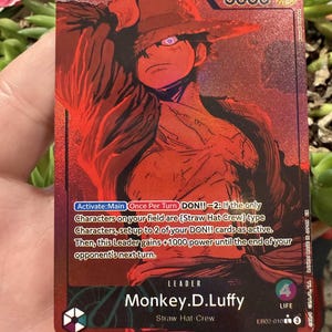 May include: A red trading card featuring a character illustration of Monkey D. Luffy from the Straw Hat Crew. The card has a 5000 power rating and includes game text. The card is part of the EB02-010 set.