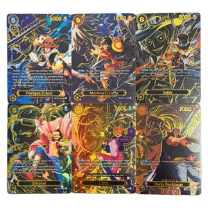 May include: A collection of six trading cards featuring characters from the One Piece anime series. The cards have a gold and blue color scheme with character illustrations and text. Each card has a different character name.