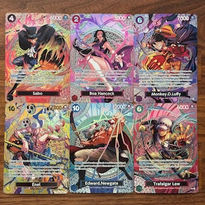Puede incluir: Seis coloridas cartas coleccionables con personajes de la serie de anime One Piece. Cada carta muestra una ilustración de personaje, un nombre y valores numéricos. Las cartas tienen un acabado holográfico.