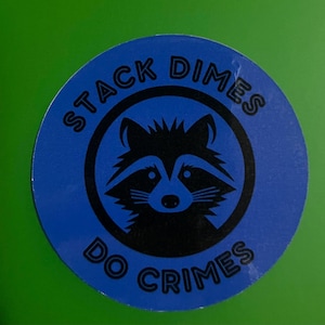 May include: A blue and black round sticker with a raccoon illustration and the text "Stack Dimes Do Crimes".