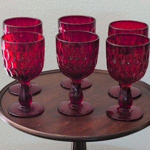 Puede incluir: Un juego de seis copas de cristal rojo intenso con un patrón de panal texturizado en el exterior de los cuencos. Cada copa tiene un tallo corto y grueso y una base circular, lo que proporciona una apariencia uniforme a este conjunto.