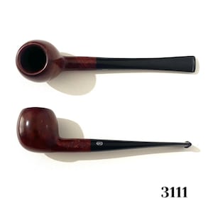 May include: Two tobacco pipes. The bowls are a dark reddish-brown, transitioning to black stems. One pipe is positioned horizontally, the other at an angle. The number "3111" is printed in black at the bottom.