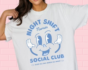 Puede incluir: Camiseta blanca con un gráfico azul de una cara de dibujos animados con el texto "Night Shift Nurses Social Club" y "Sleep all day, Nurse all night".