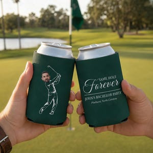 May include: Two dark green foam can coolers. One features a white line drawing of a golfer with a caricature head. The other displays the white text: SAME HOLE Forever, JOHN'S BACHELOR PARTY, Pinehurst, North Carolina, in a script and serif font.