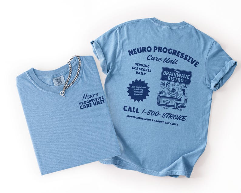 Puede incluir: Dos camisetas azul claro. Una est&aacute; doblada, mostrando el texto "Neuro Progressive Care Unit" y un collar de cadena plateada. La otra, desplegada, muestra la parte trasera con texto y un gr&aacute;fico de restaurante. El texto incluye "Call 1-800-STROKE".