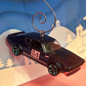May include: A blue and black toy car ornament with a white number 54 on the side. The car is hanging from a silver hook.