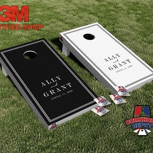 May include: Two cornhole boards, one black and one white, with the names "Ally and Grant" and the date "April 11, 2020" printed on them. The boards are on a green lawn, with bean bags and a logo in the lower right corner.