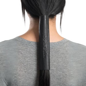 May include: Black leather ponytail holder with the text "Angel Rider" embossed on it.