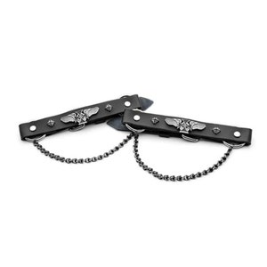 Op de afbeelding: Een paar zwarte leren motorbootschoenen met zilveren metalen accenten. Elke riem heeft een gevleugeld kruisontwerp en een ketting die aan de metalen ringen is bevestigd.