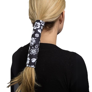 May include: Black and white floral ponytail holder with a white hibiscus pattern.