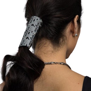 May include: Black and white patterned hair tie with a geometric design. The hair tie is made of a thick, durable material and has a secure clasp.