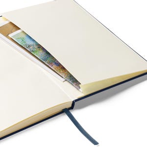 May include: A navy blue hardcover journal with a cream-colored interior and a ribbon bookmark. The journal has a pocket on the inside cover.