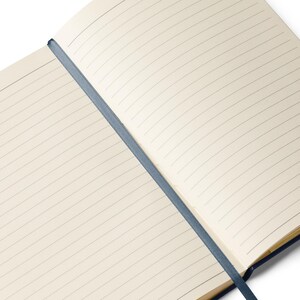 May include: A blank, lined notebook with a blue spine and a blue ribbon bookmark. The notebook is open to a fresh, blank page.