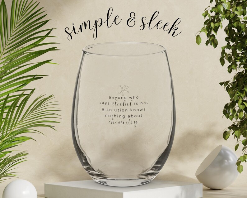 Op de afbeelding: Een helder glazen wijnglas met de tekst "anyone who says alcohol is not a solution knows nothing about chemistry" gedrukt op de zijkant.