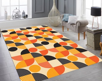 May include: A geometric patterned rug with orange, yellow, and black circles and semi-circles on a cream background.